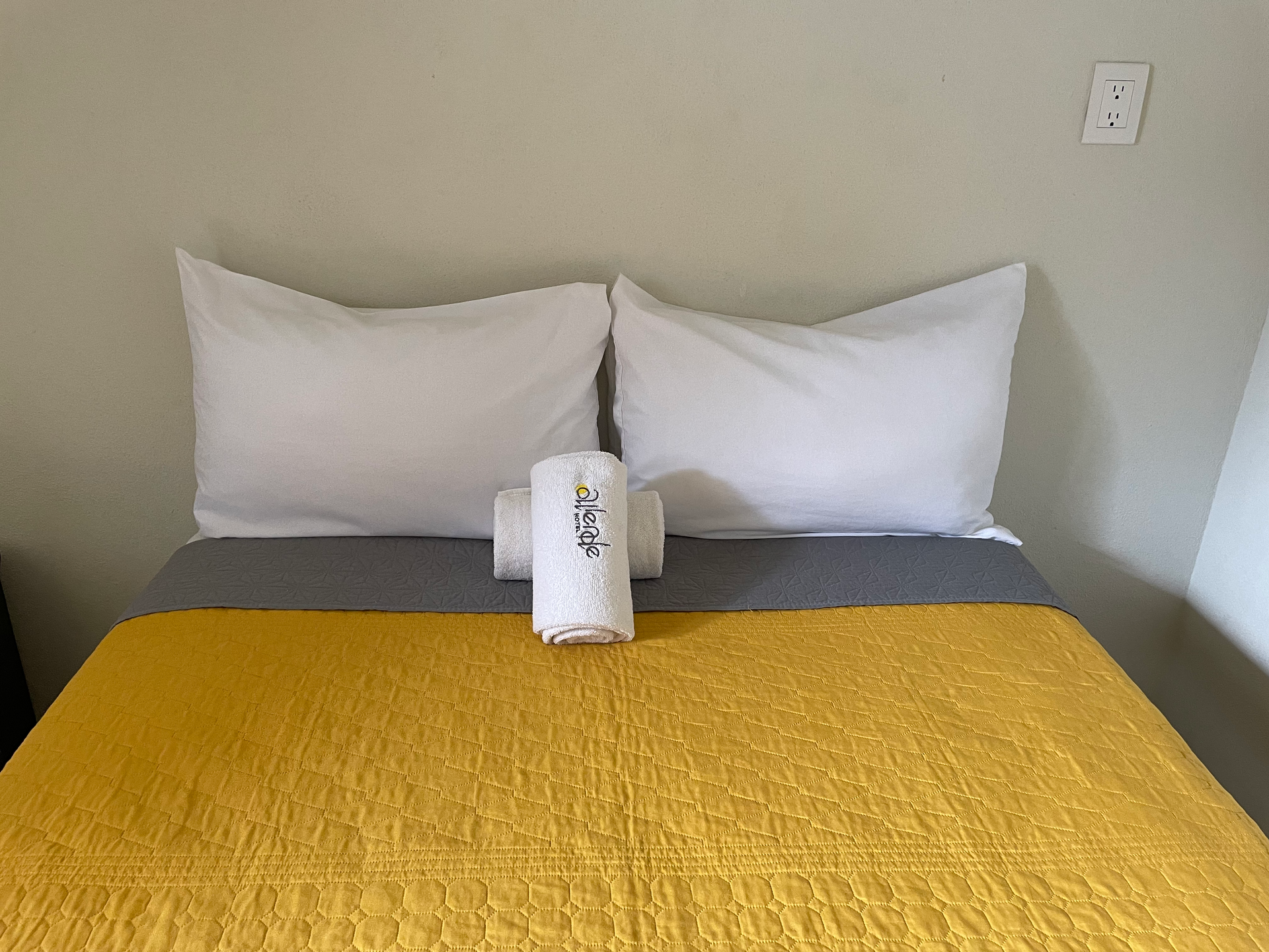 A bed with a yellow blanket and white pillows