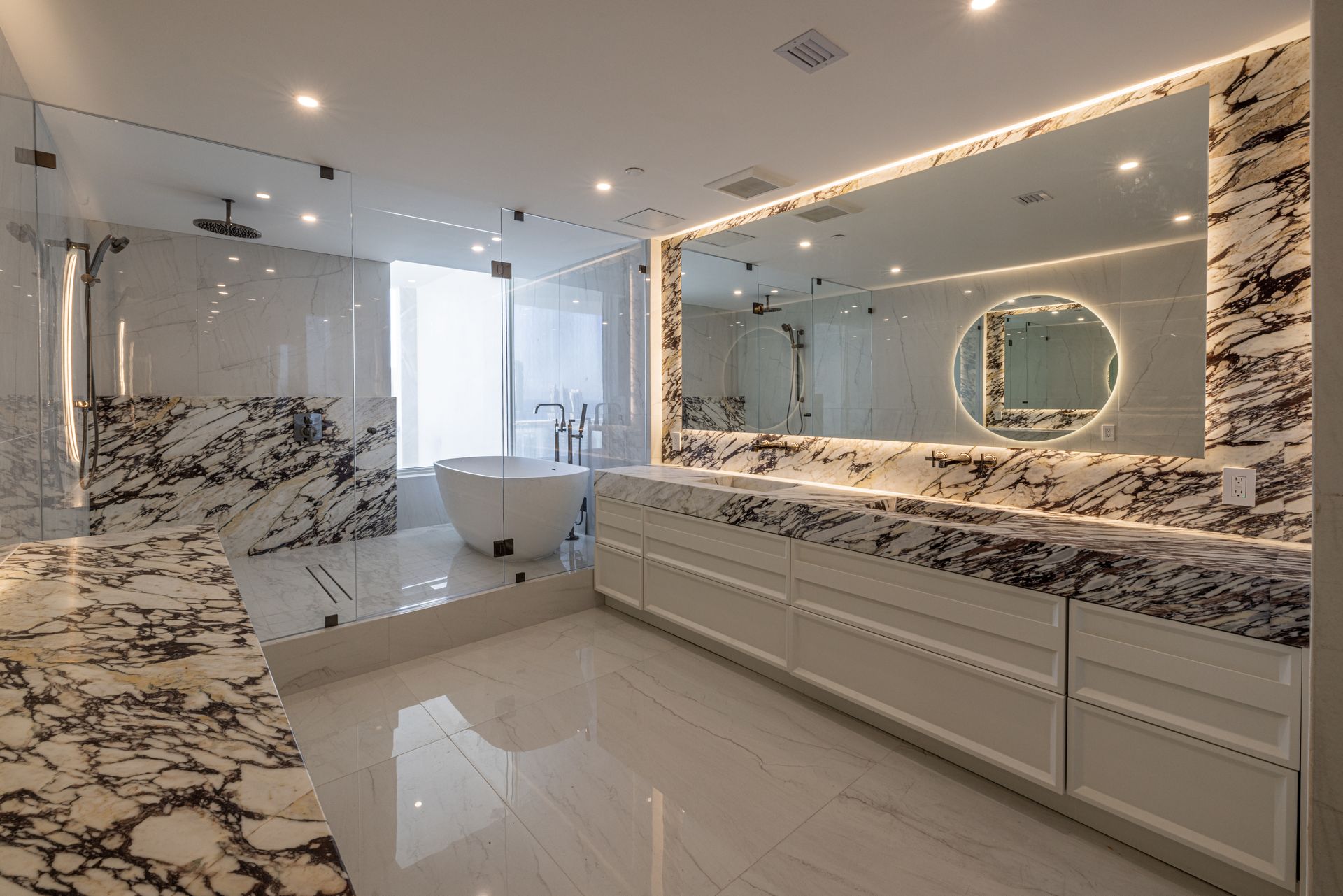 A bathroom with two sinks , a tub , and a large mirror.