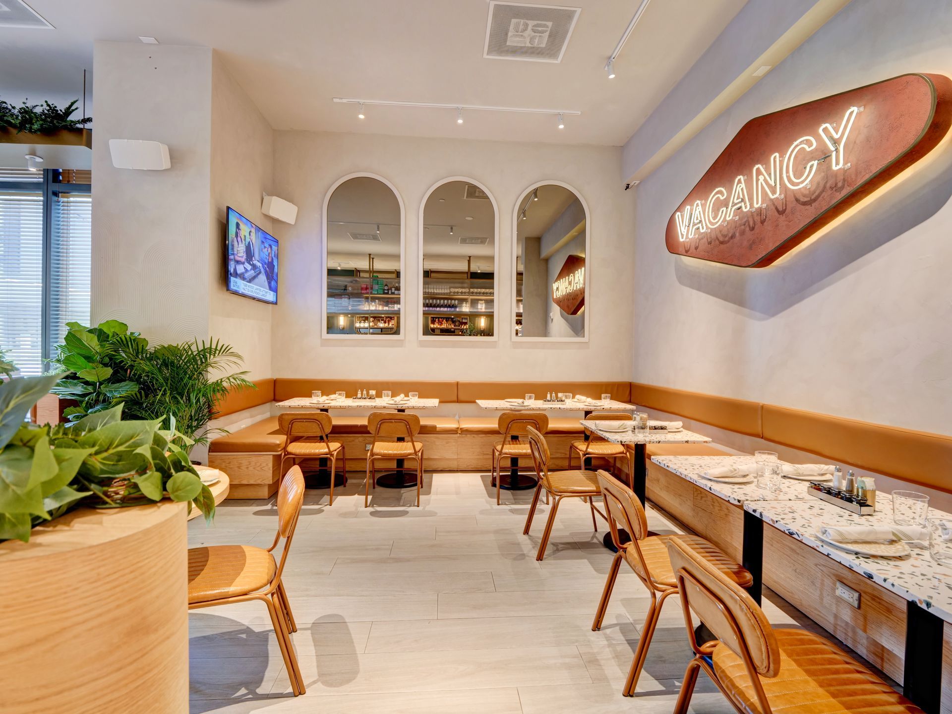 A restaurant with tables and chairs and a sign on the wall.