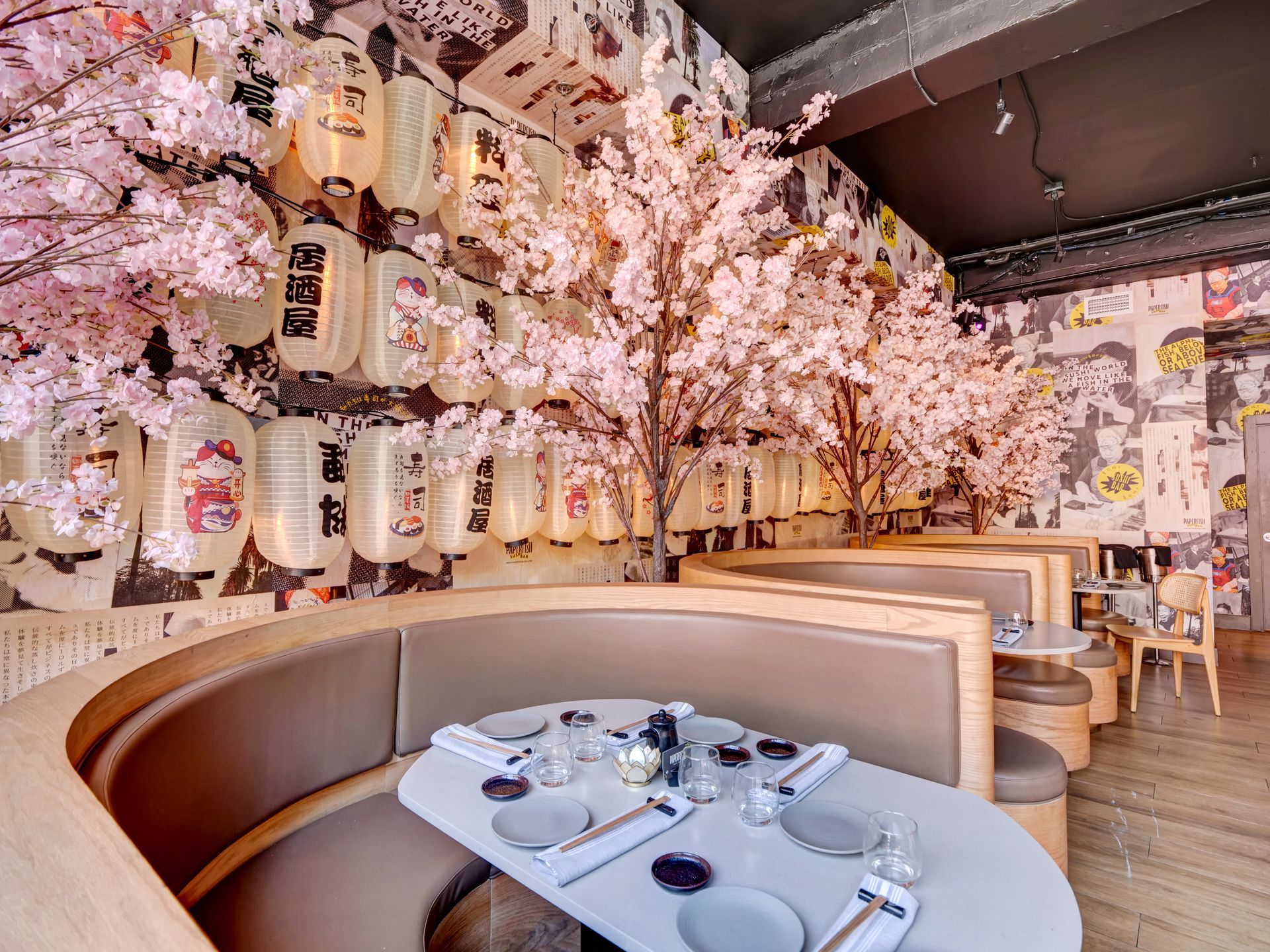 A restaurant with cherry blossom trees and lanterns on the wall.