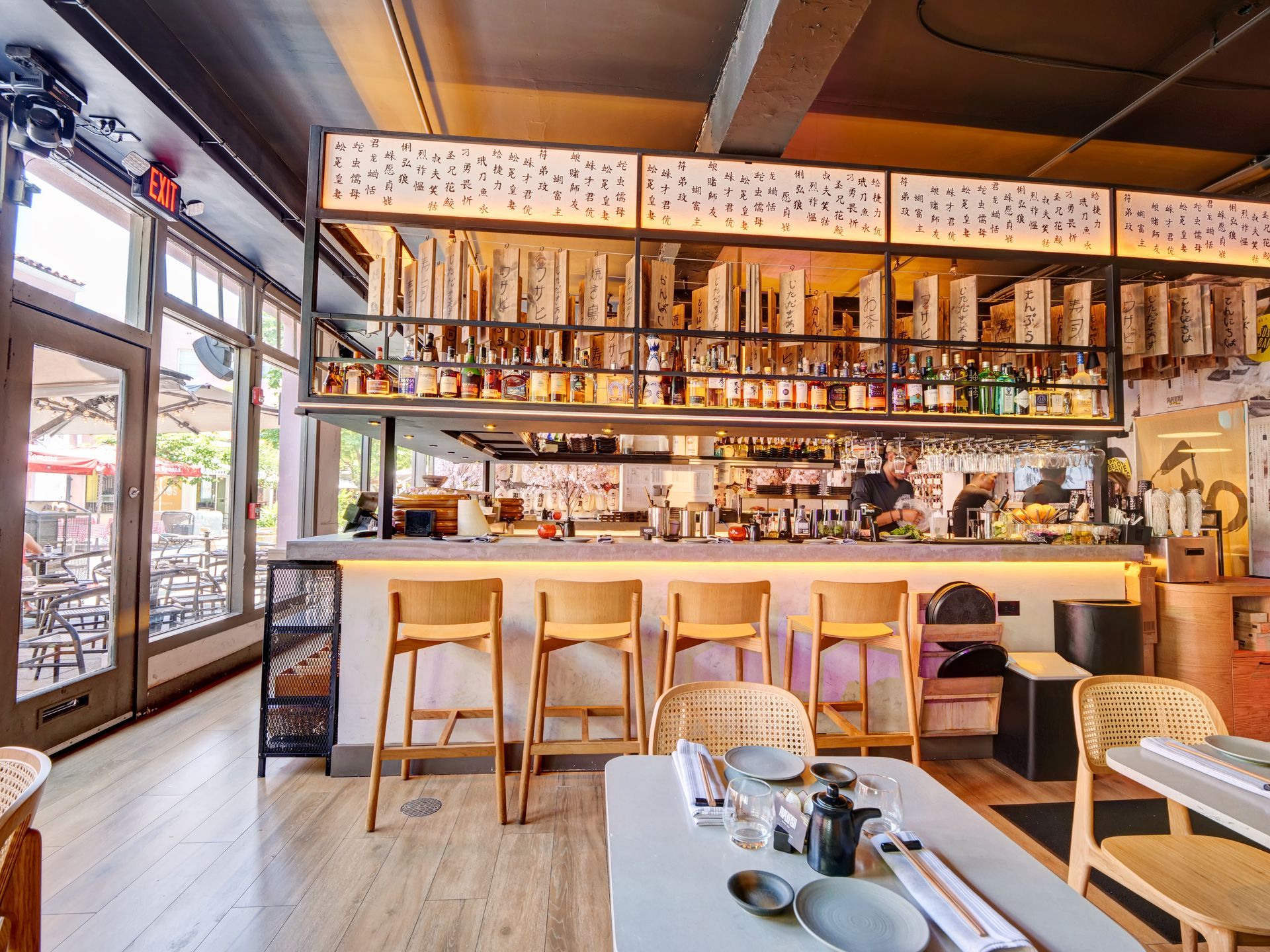 A restaurant with a long bar and tables and chairs.