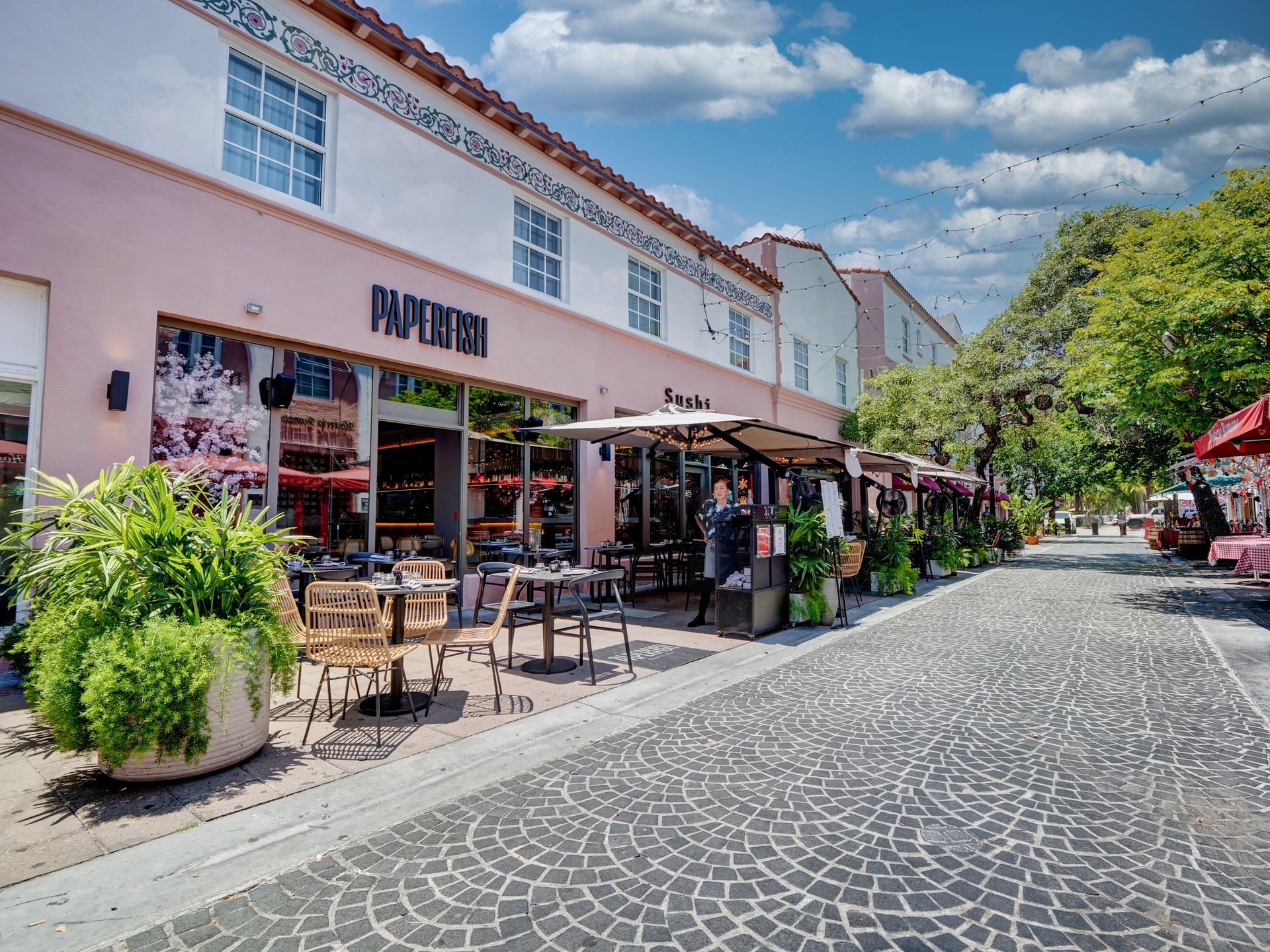 A restaurant with tables and chairs outside on a cobblestone street.