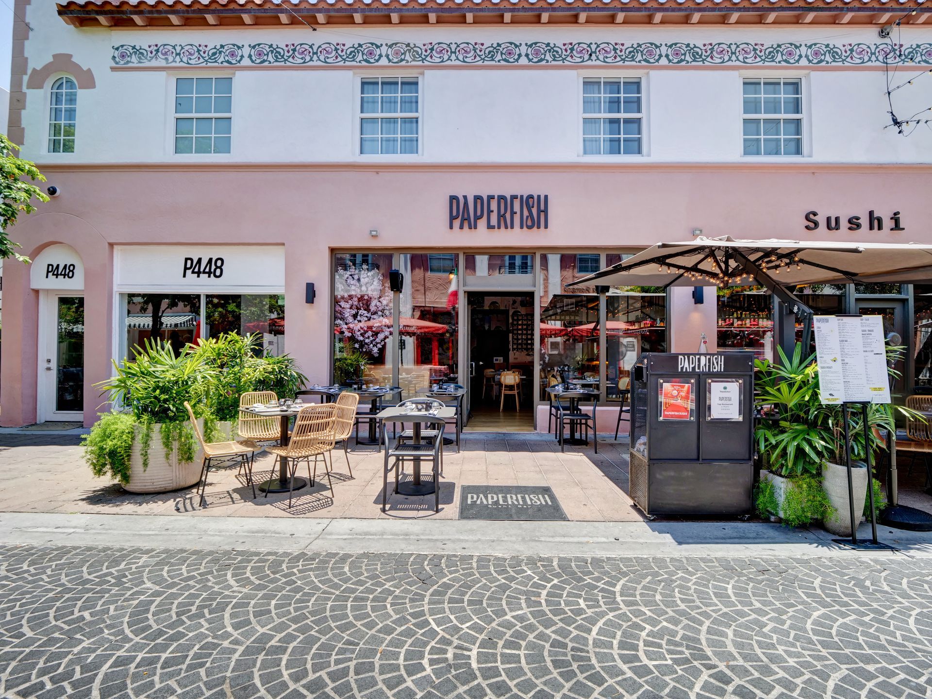 The front of a restaurant with tables and chairs outside.