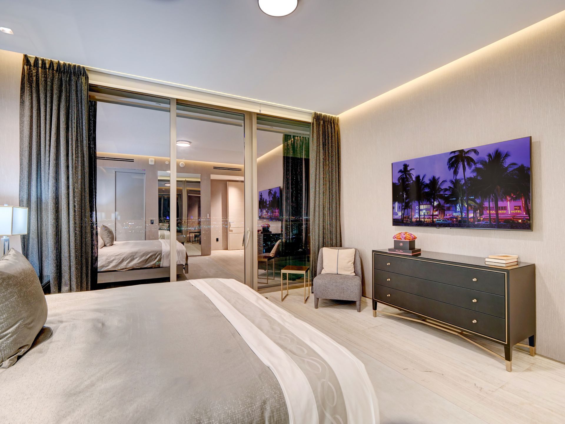 A bedroom with a large bed , dresser , chair and television.