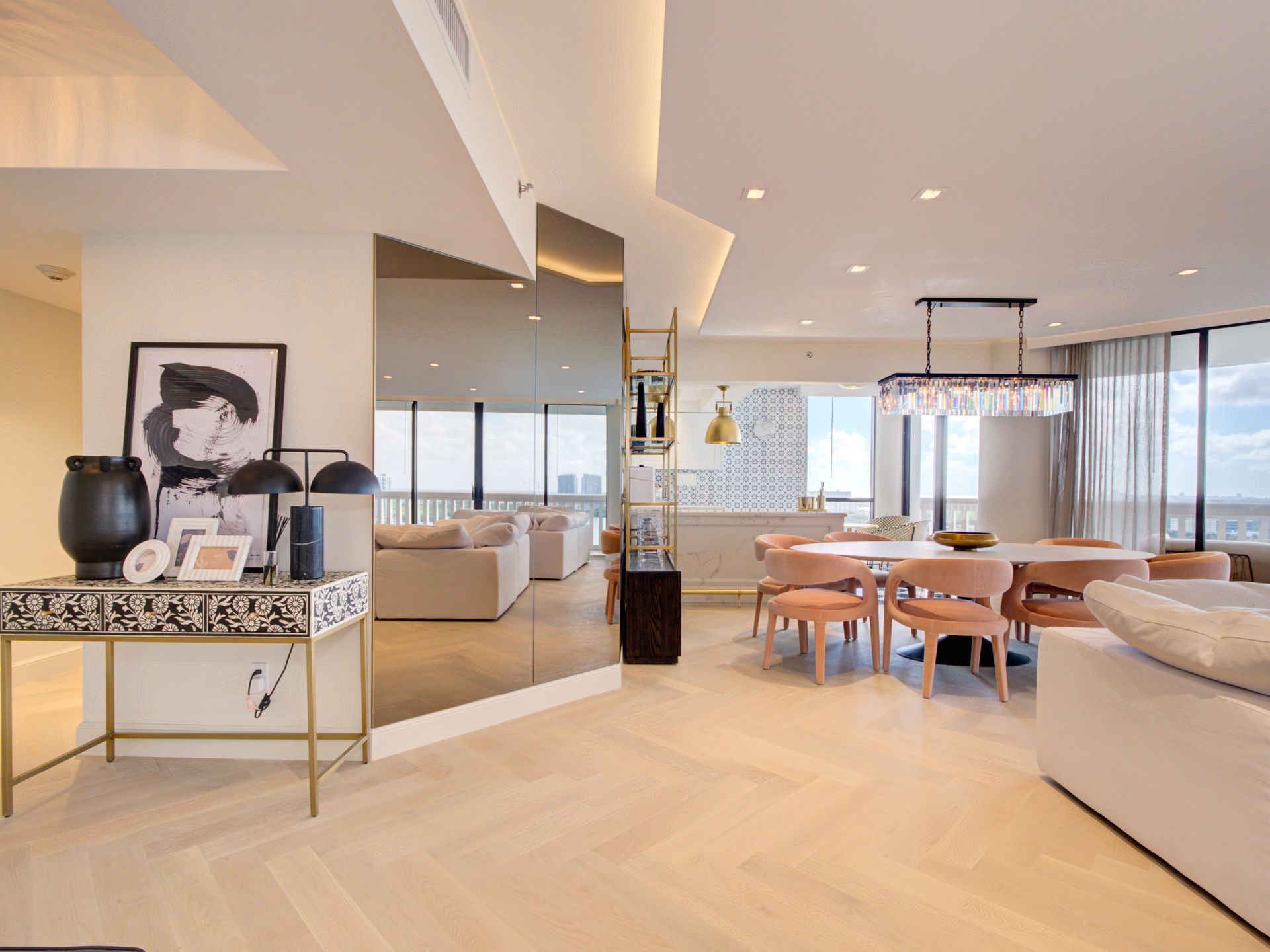 A living room with a dining table and chairs and a large mirror.