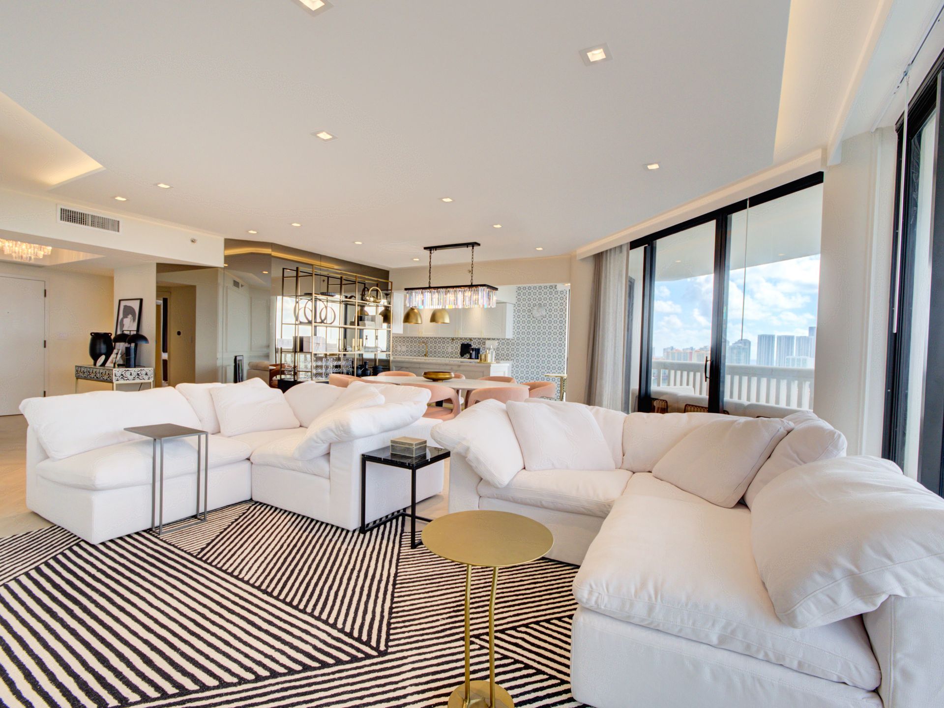 A living room with white furniture and a black and white rug