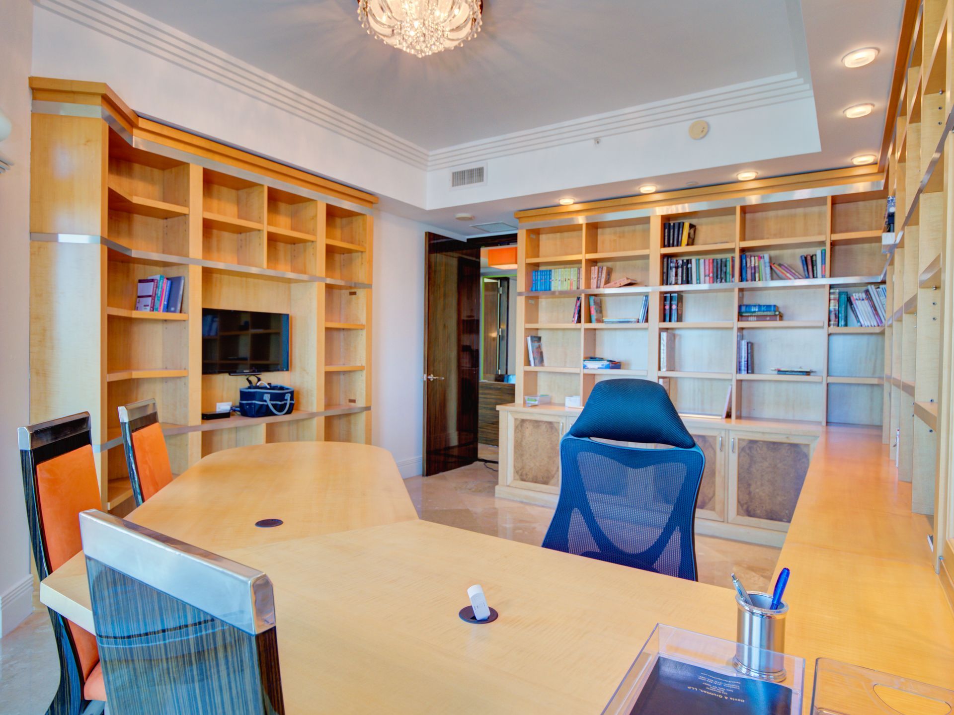 A room with a table , chairs , shelves and a television.