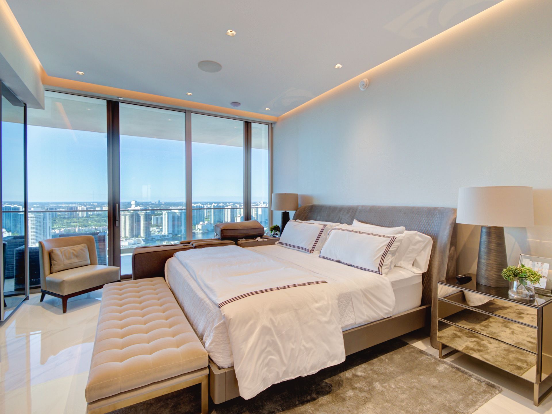 A bedroom with a large bed , chairs , nightstands and a balcony.