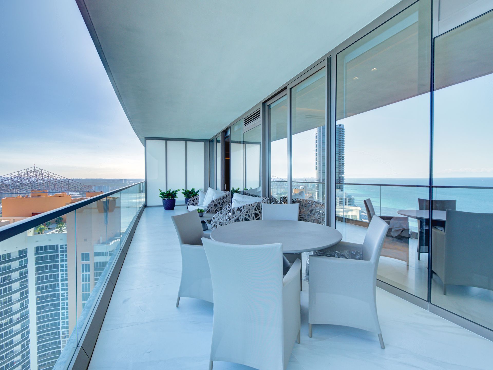 A large balcony with a table and chairs overlooking the ocean.