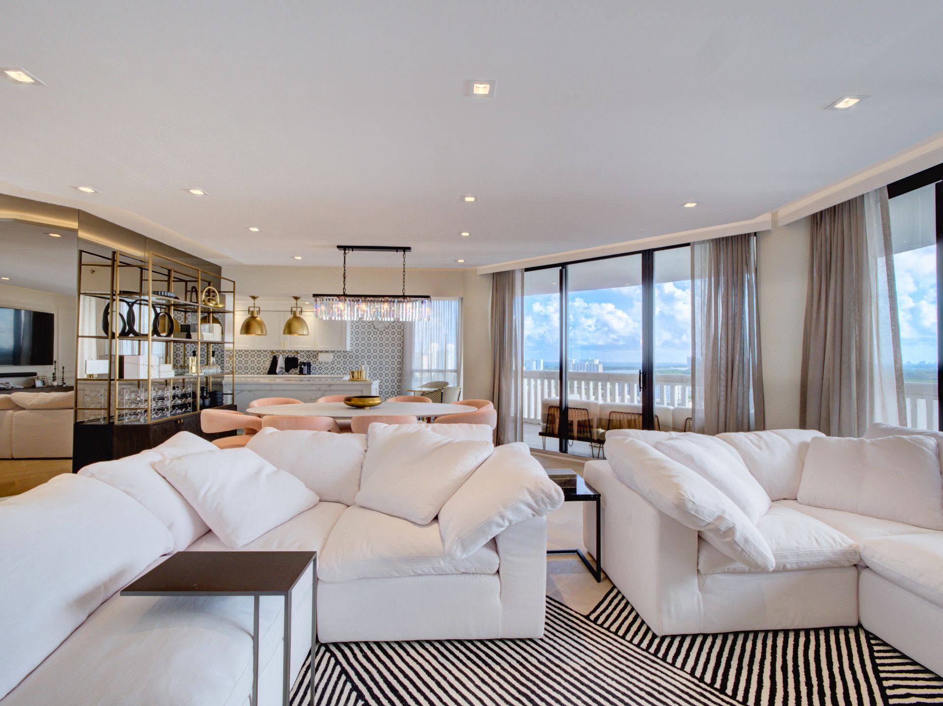 A living room with white couches and a black and white rug.