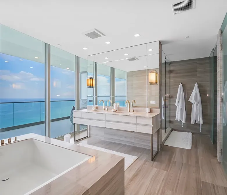A bathroom with two sinks and a bathtub with a view of the ocean.
