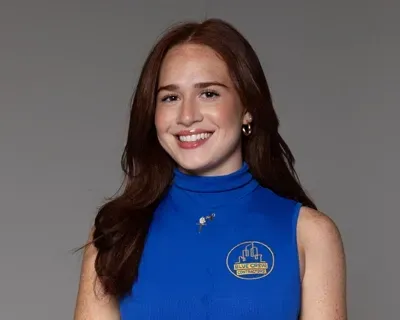 A woman is wearing a blue tank top and smiling.