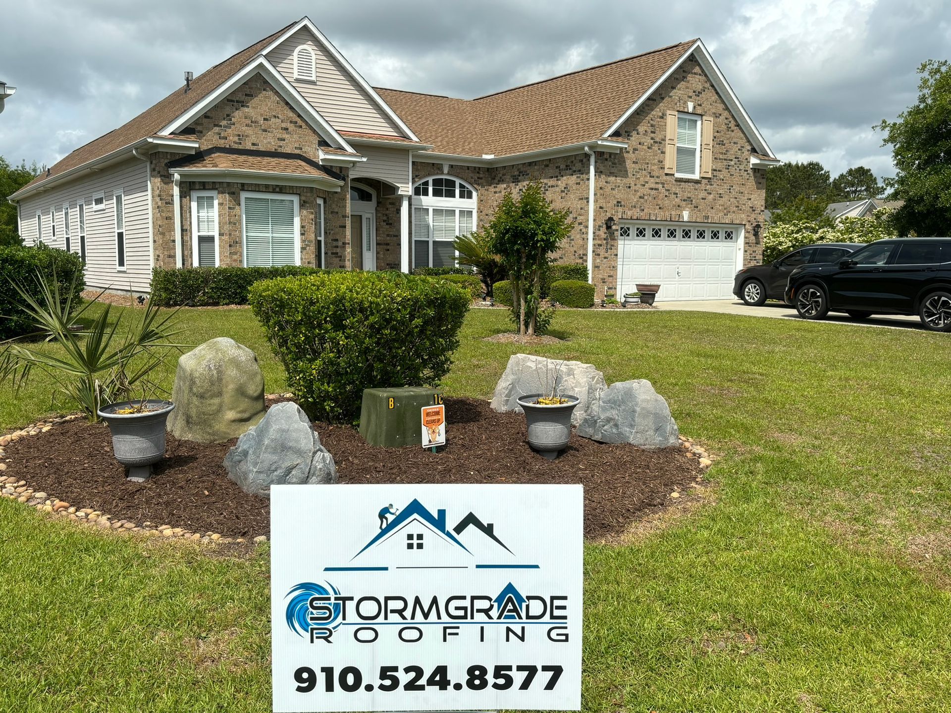 A large brick house with a sign in front of it.