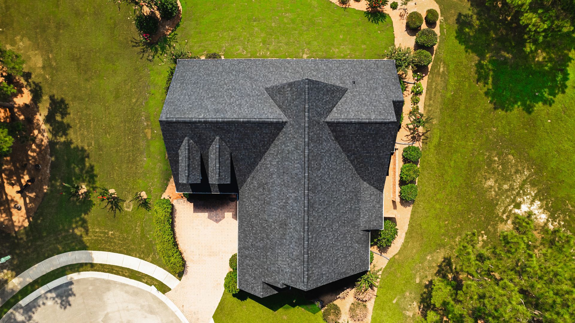 An aerial view of a house with a black roof in a residential area.