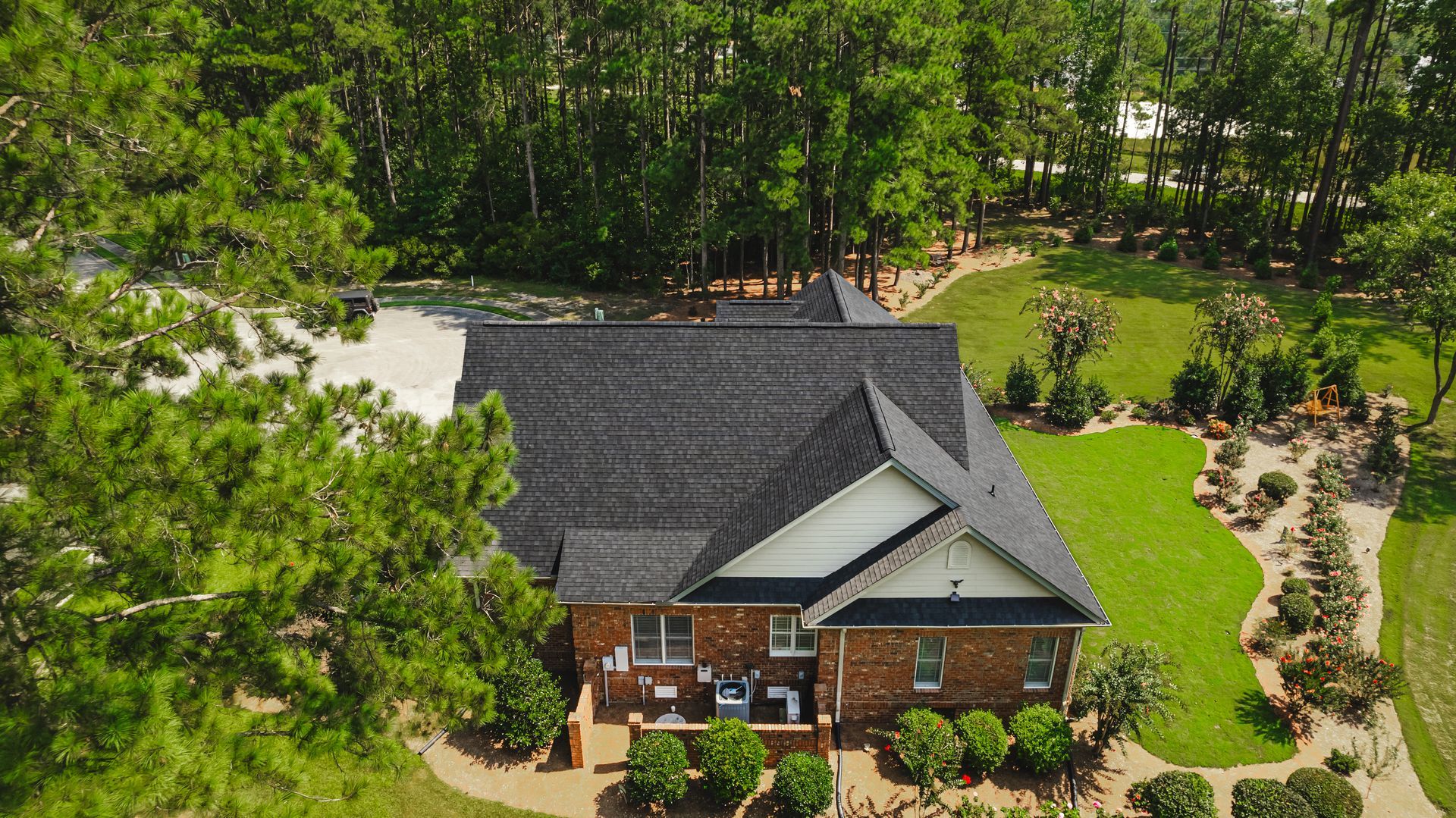 An aerial view of a brick house surrounded by trees and grass.