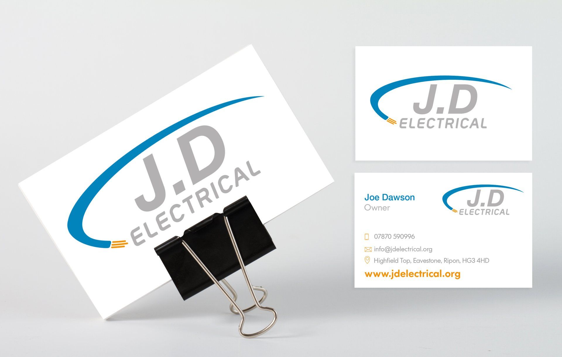 A business card for j.d electrical is sitting on top of a paper clip.