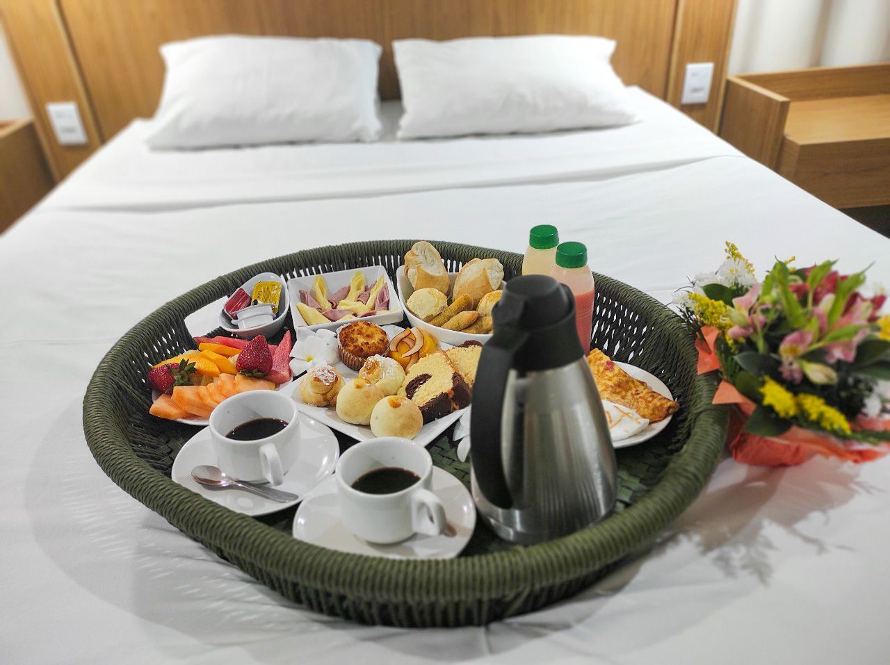 Uma bandeja de comida e café em uma cama em um quarto de hotel