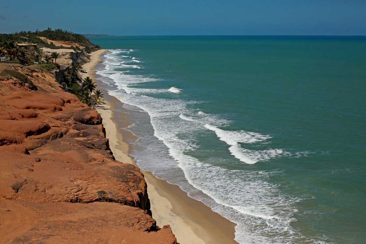 Uma vista aérea de uma praia com ondas quebrando na costa.