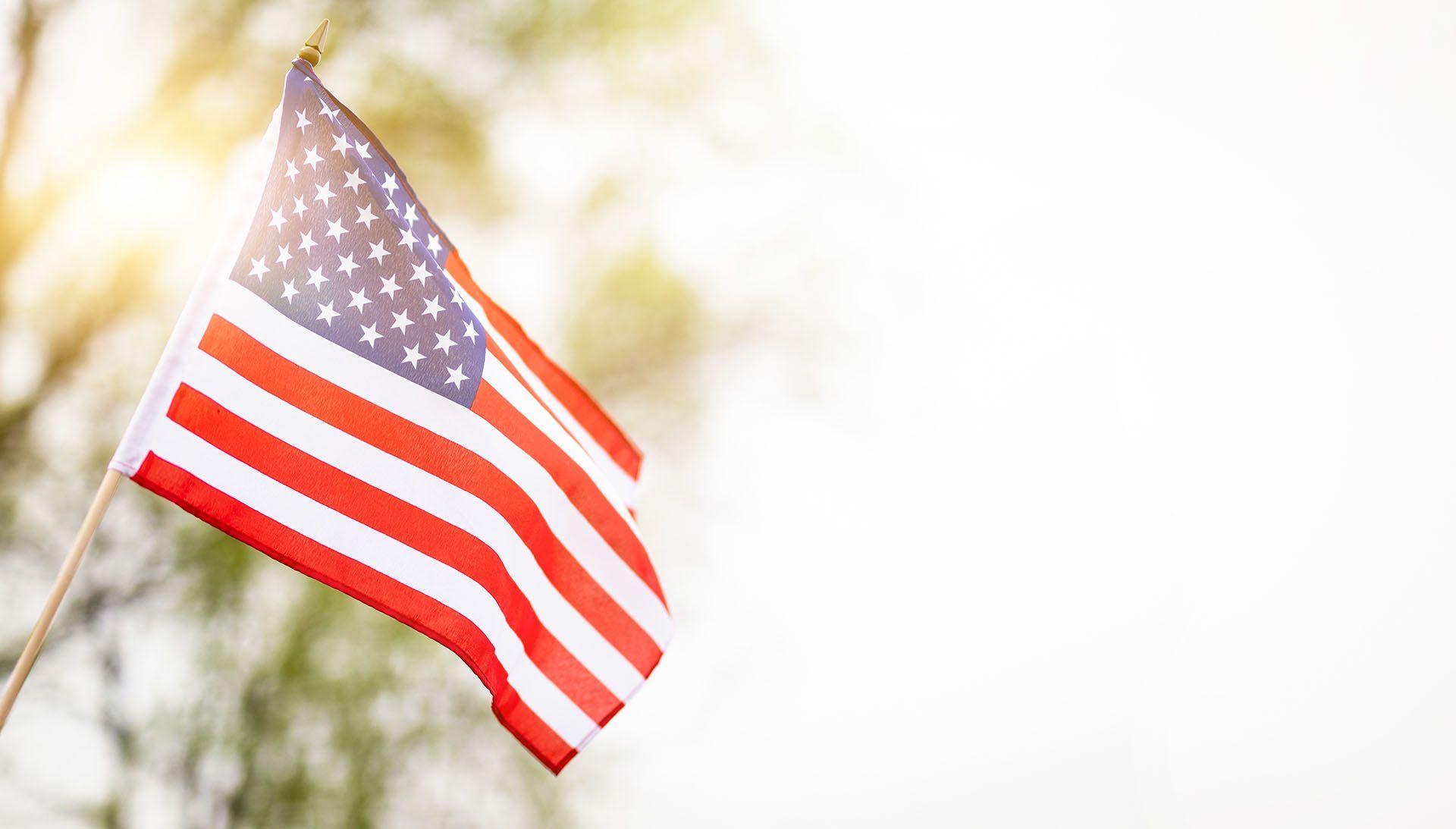 A woman is holding an american flag and a rose at a funeral.
