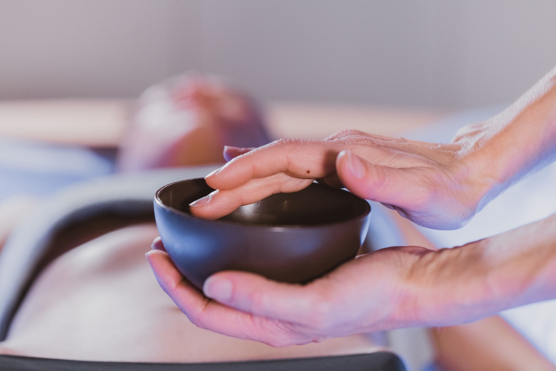 Una persona tiene una ciotola tra le mani mentre riceve un massaggio.