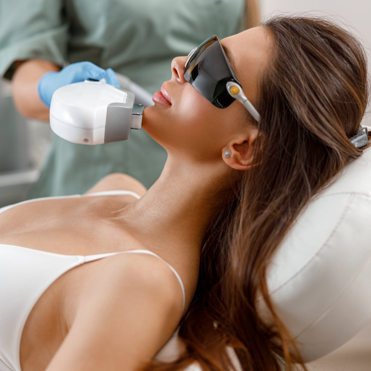 Una donna che indossa occhiali da sole si sta sottoponendo a un trattamento laser sul viso.