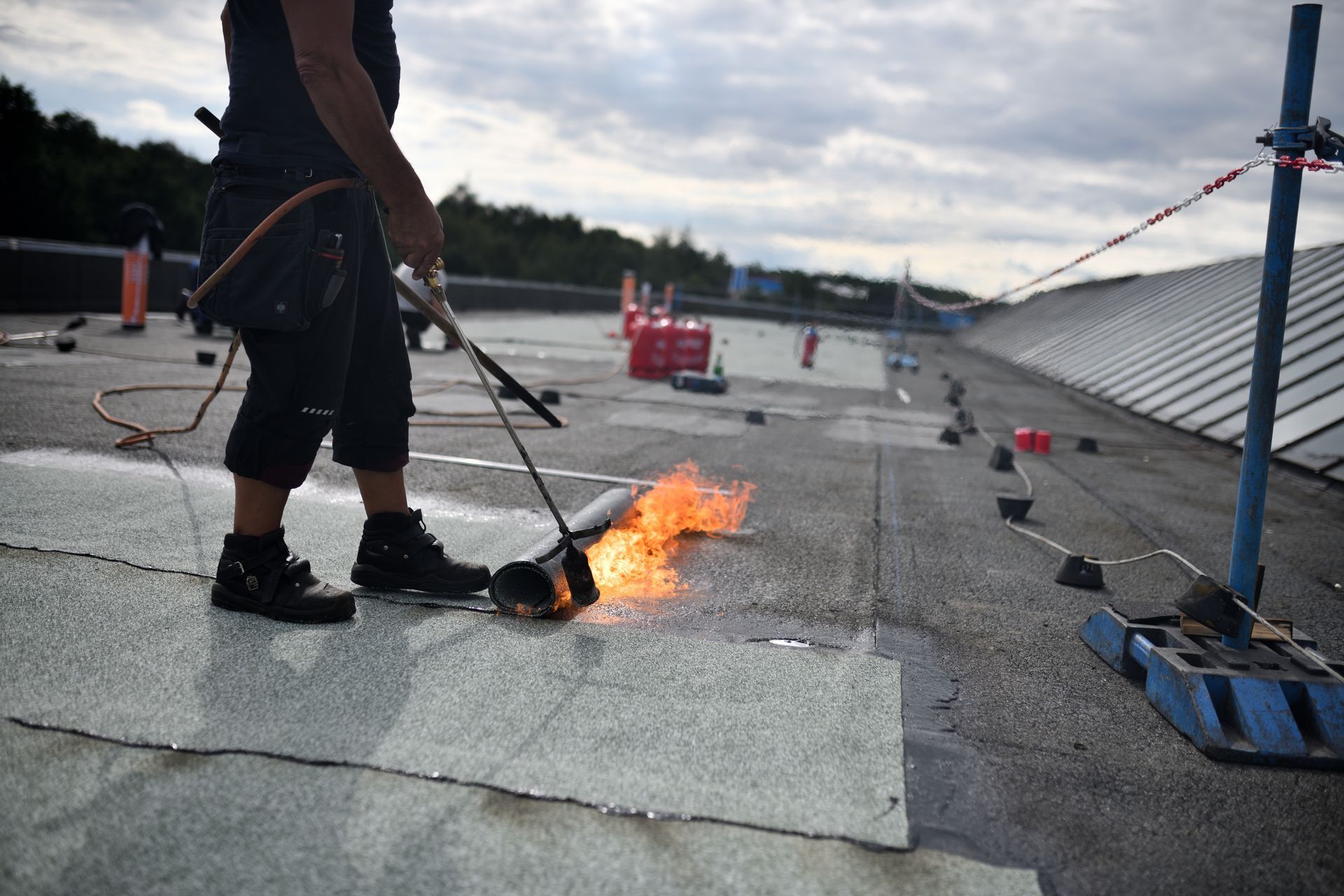 Roofer using a torch to seal roofing material on a commercial rooftop.