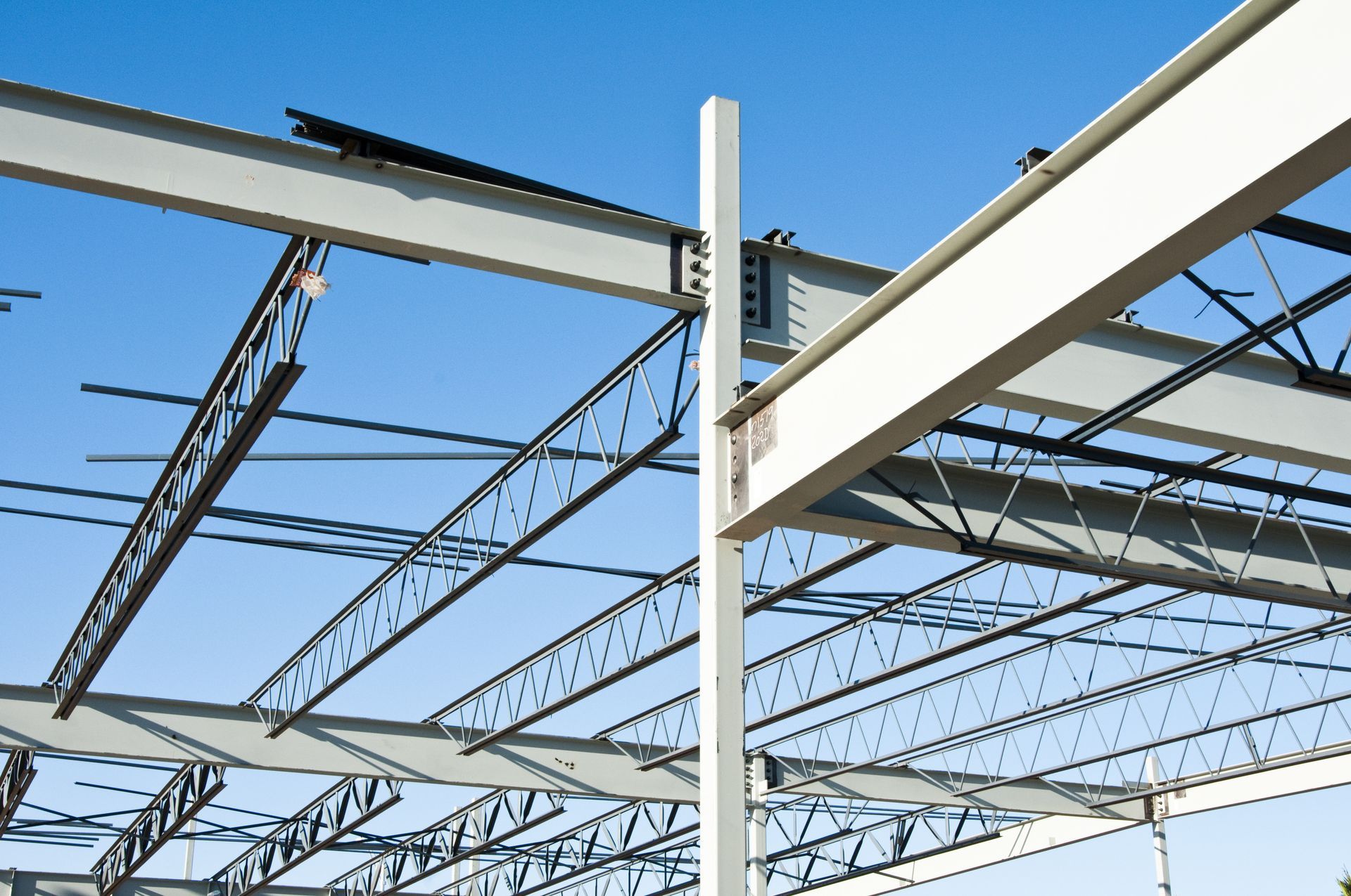 Steel beams and trusses, constructing a building against a blue sky.