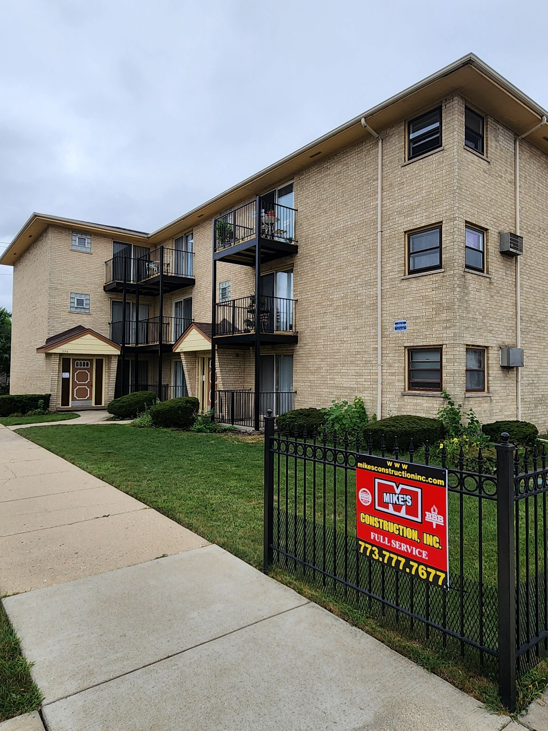 A large apartment building with a red sign in front of it.