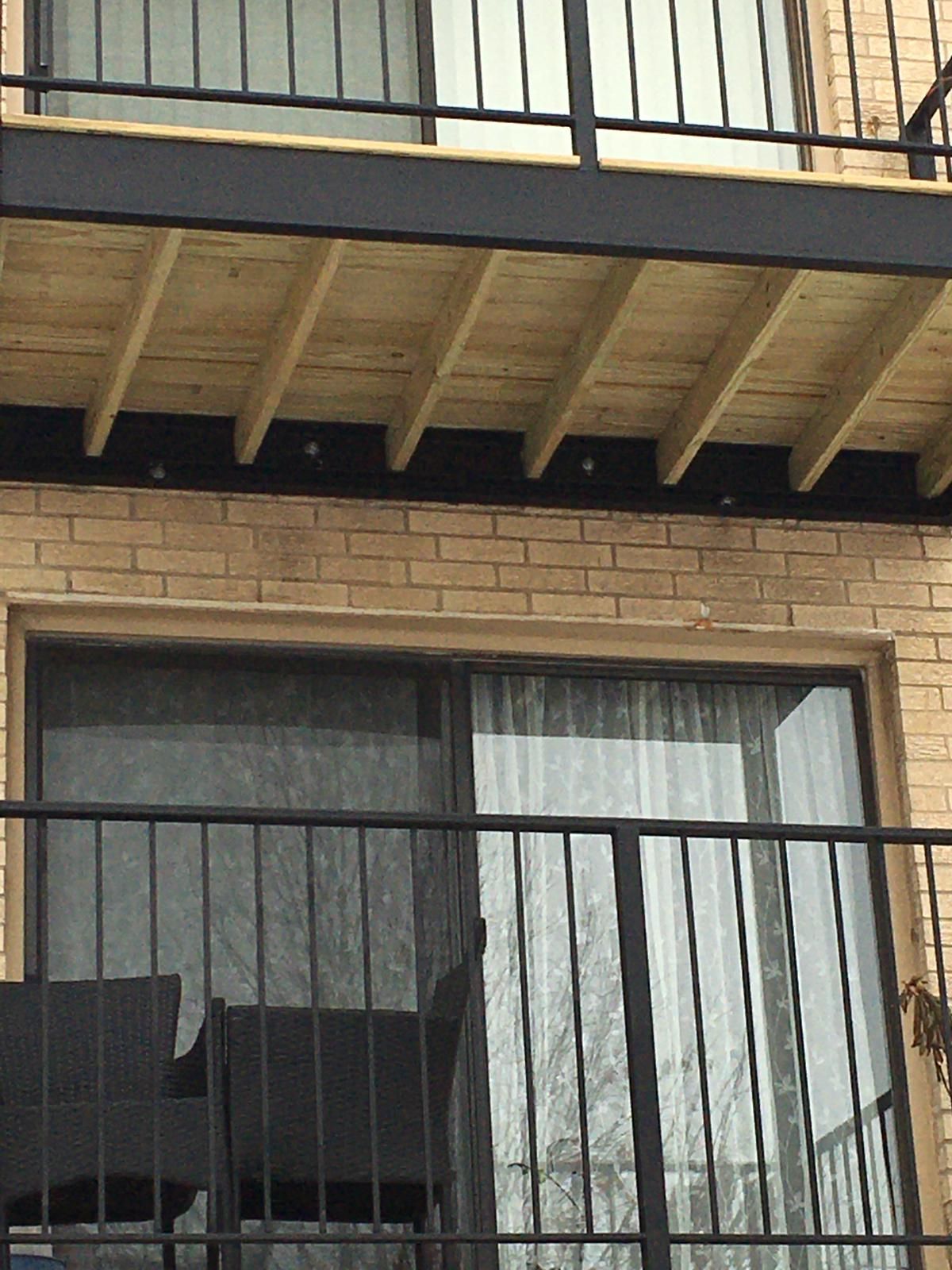 A balcony with a sliding glass door and a metal railing on a brick building.