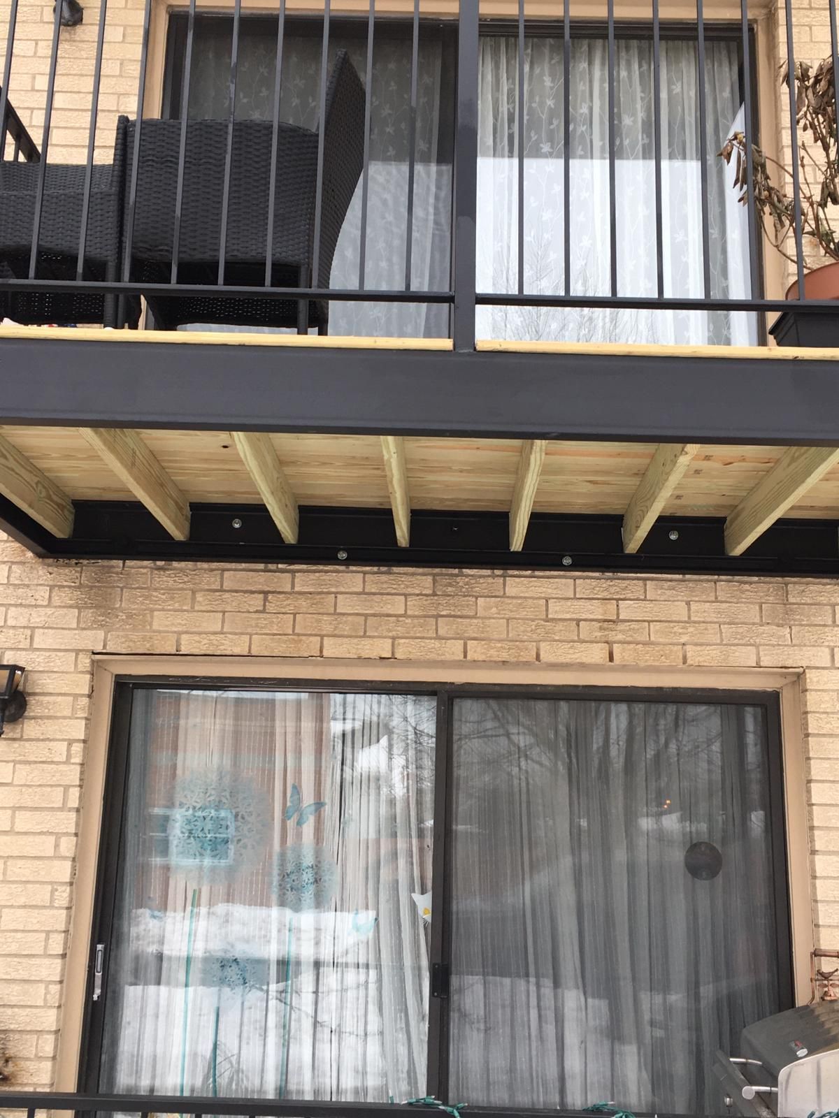 A balcony with a sliding glass door on a brick building.