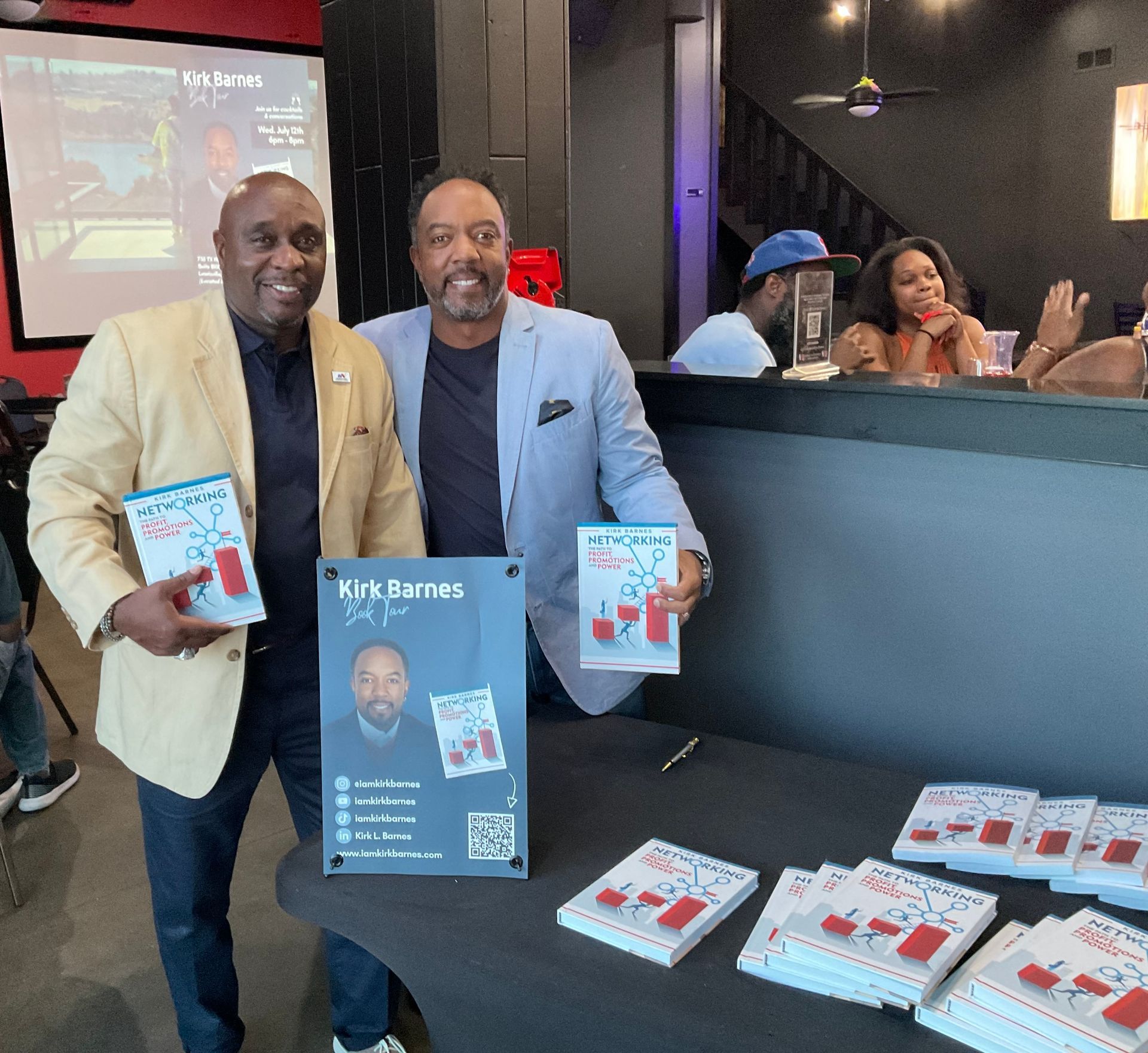Two men are standing in front of a table holding books