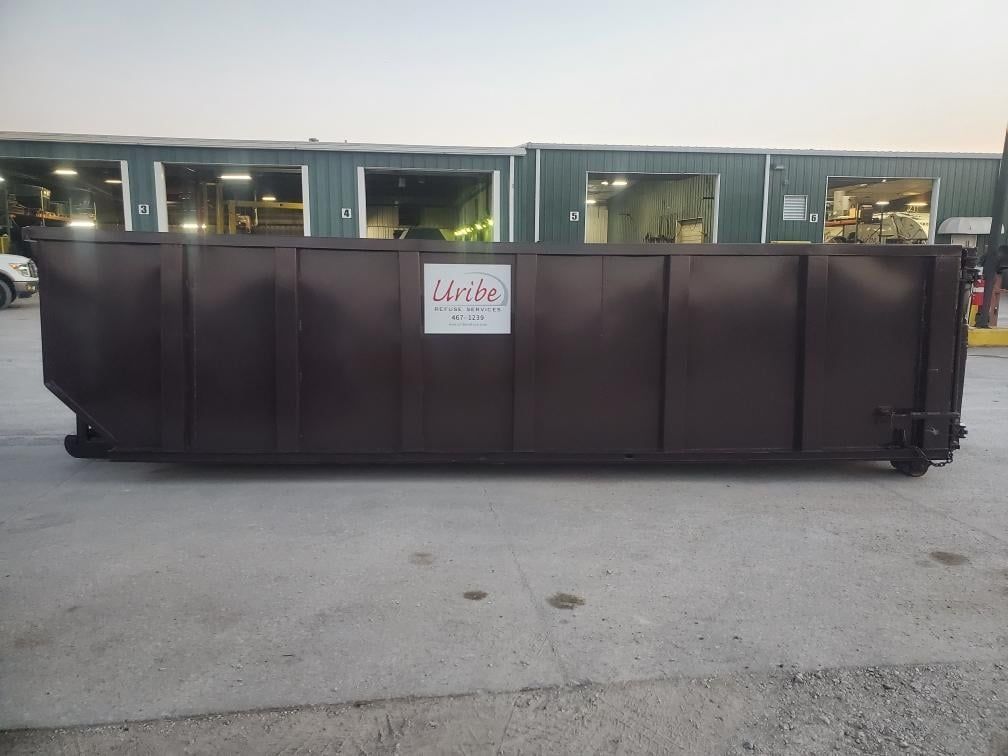 A large brown dumpster is parked in front of a building.