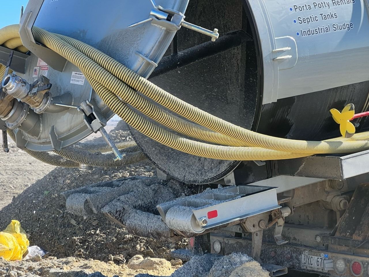 A garbage truck is covered in plastic in a garage.