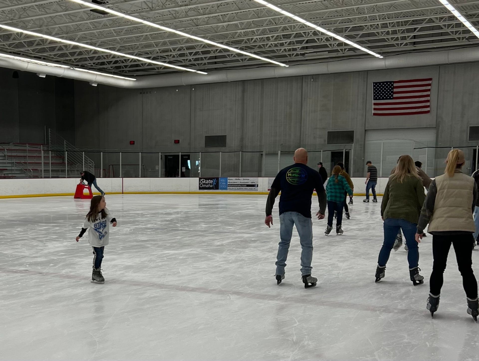 A group of people are ice skating on an indoor rink.