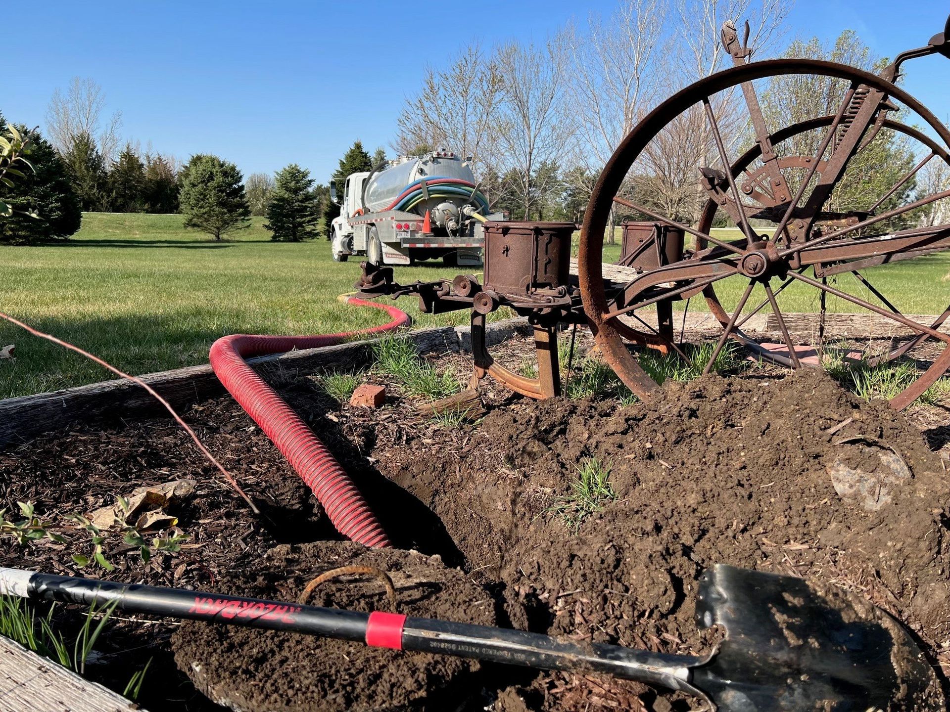A shovel is sitting in the dirt next to an old plow.