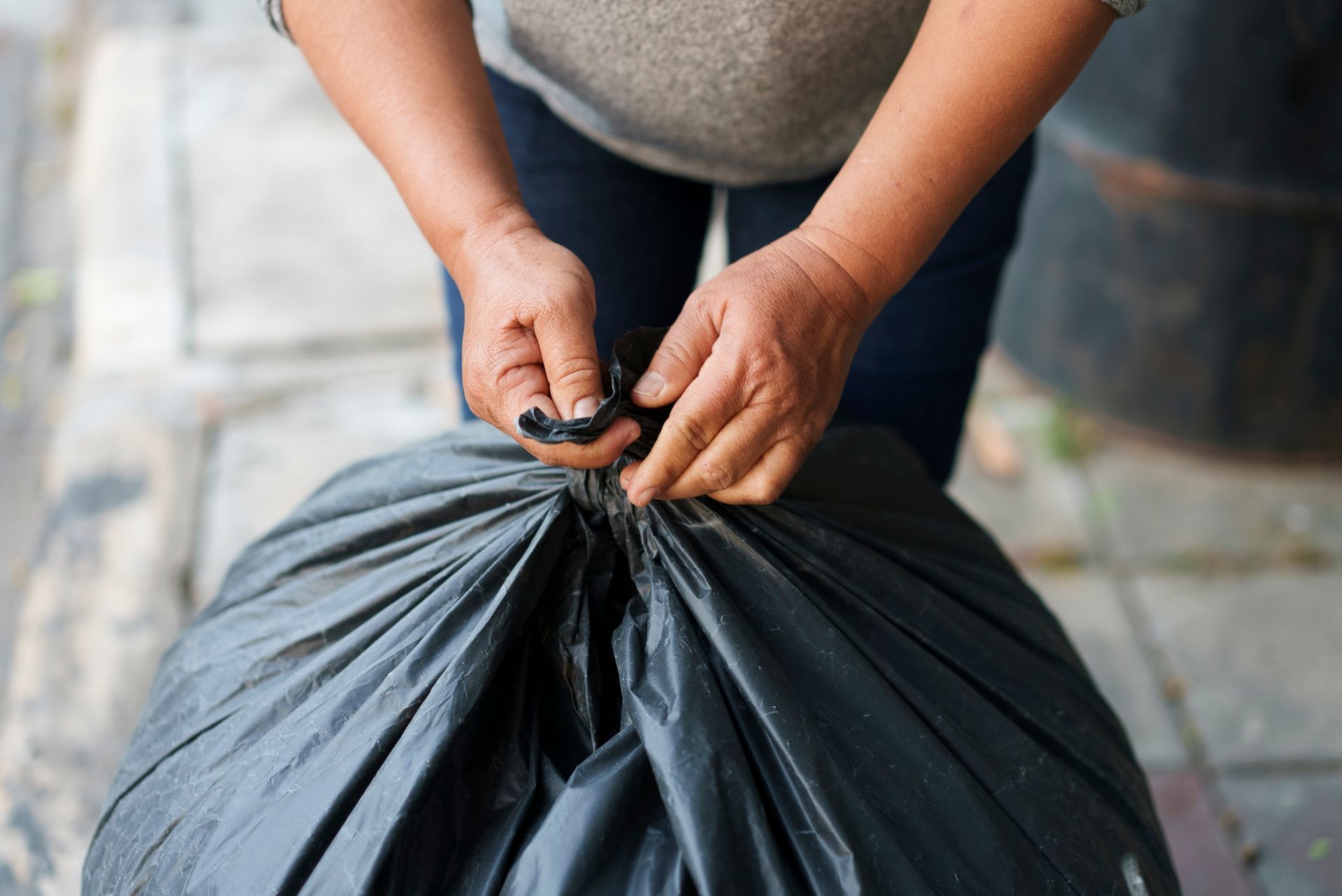 A person is tying a garbage bag with a rubber band.