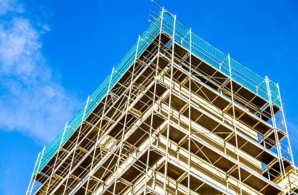 A building is being built with scaffolding and a blue sky in the background.