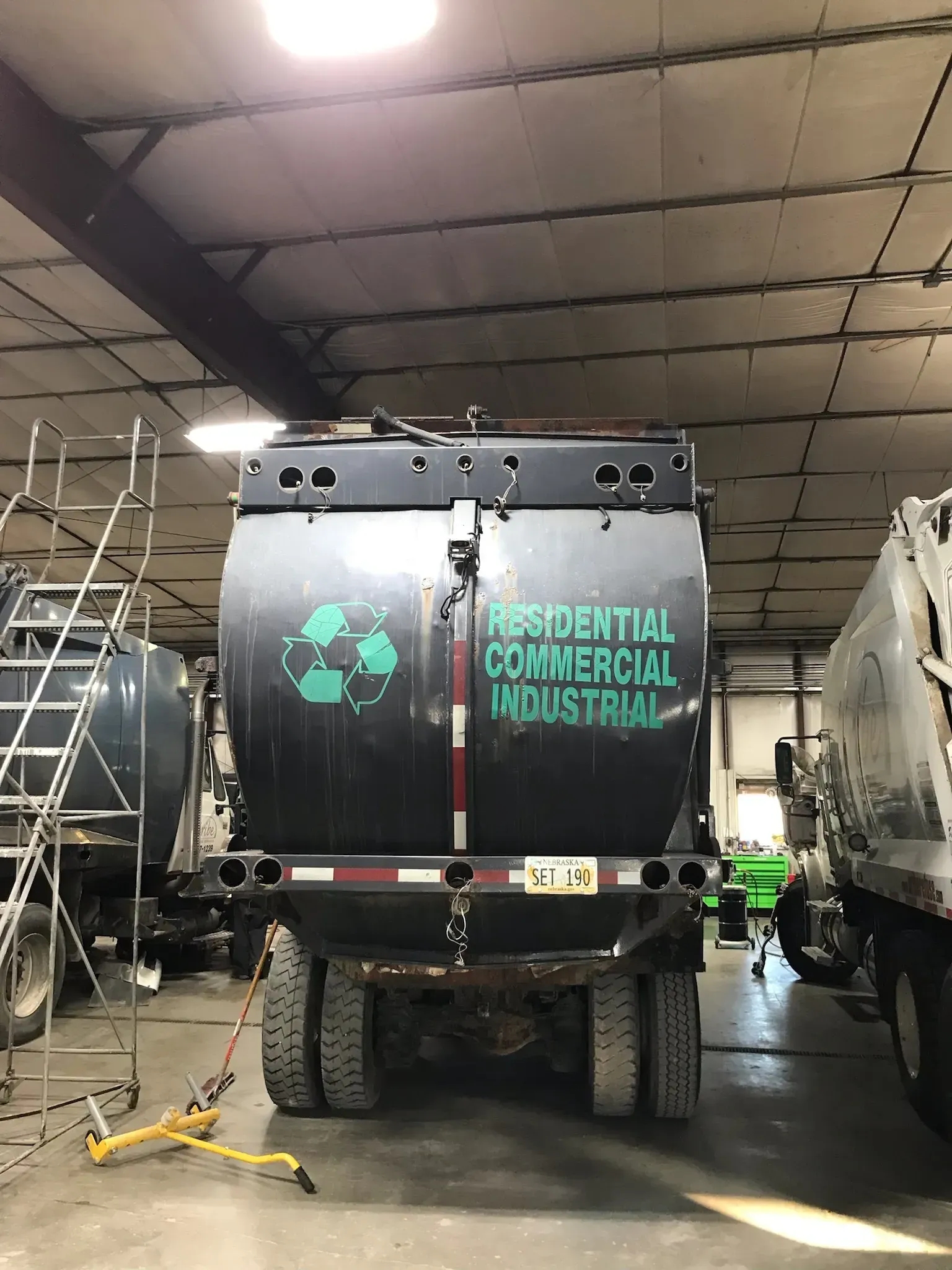 A residential commercial industrial garbage truck is parked in a garage.