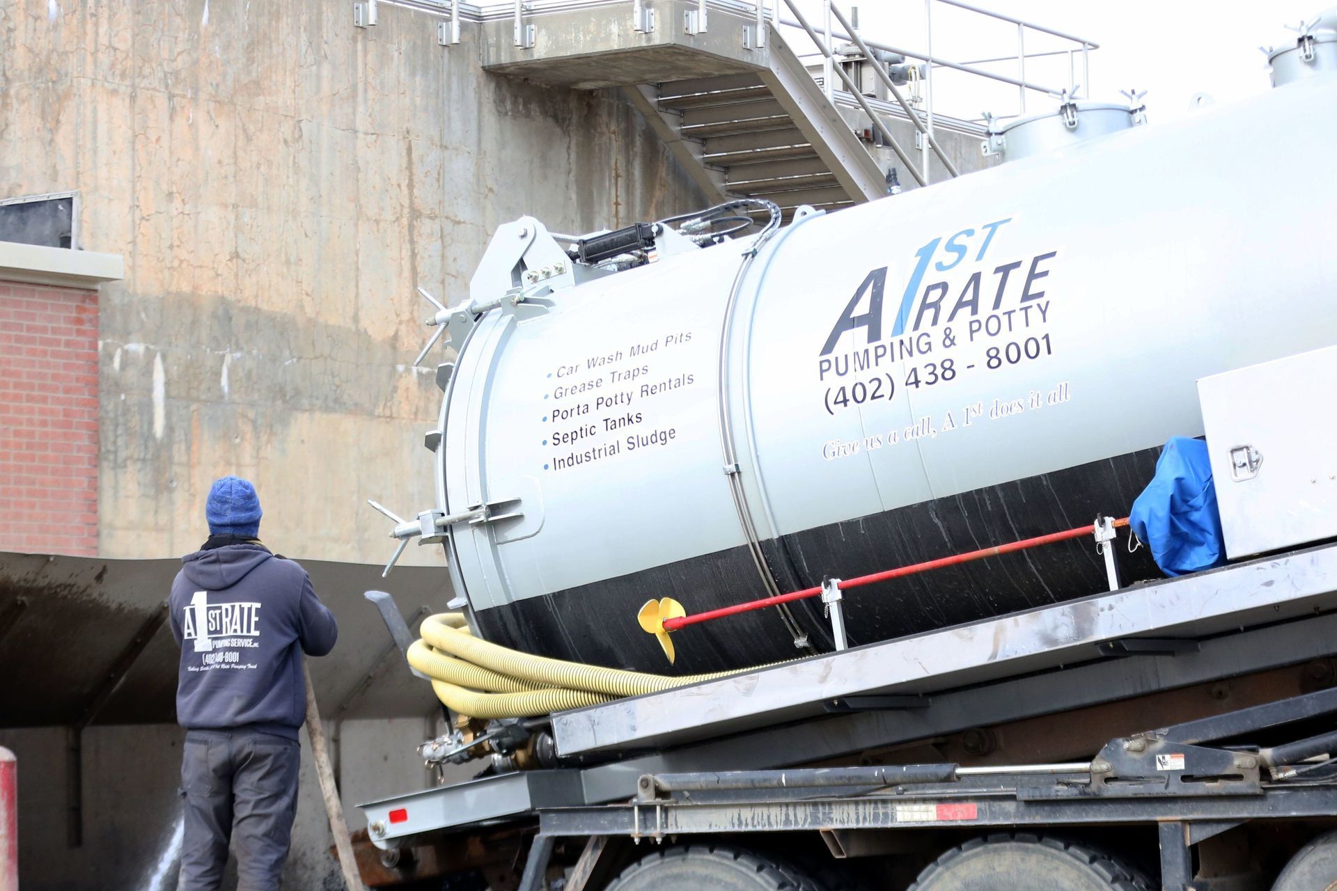 A man is standing next to a vacuum truck.