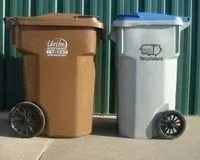 Two trash cans are sitting next to each other on a sidewalk.
