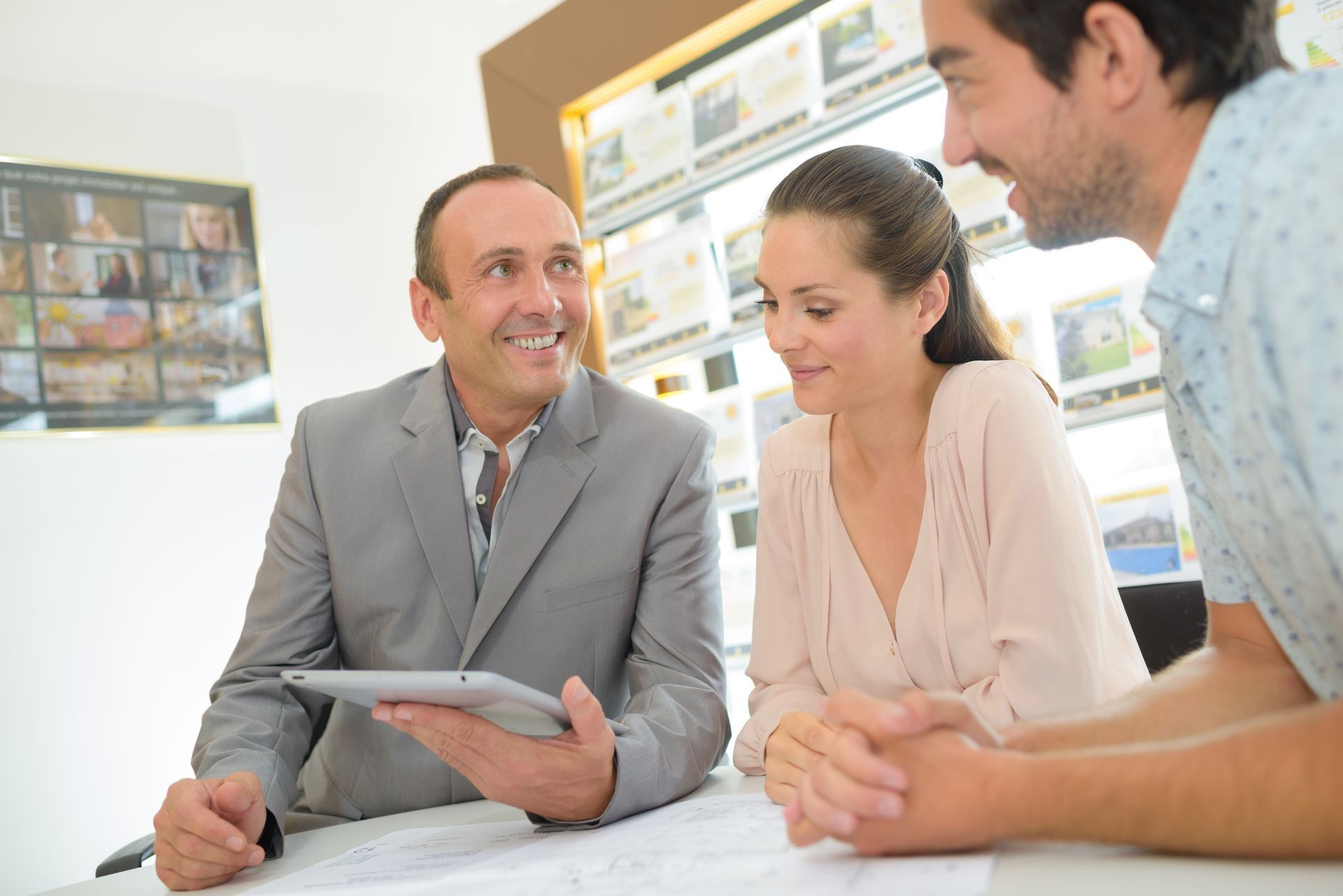 Man on phone, looking at paper. Sitting on beige couch in a living room.