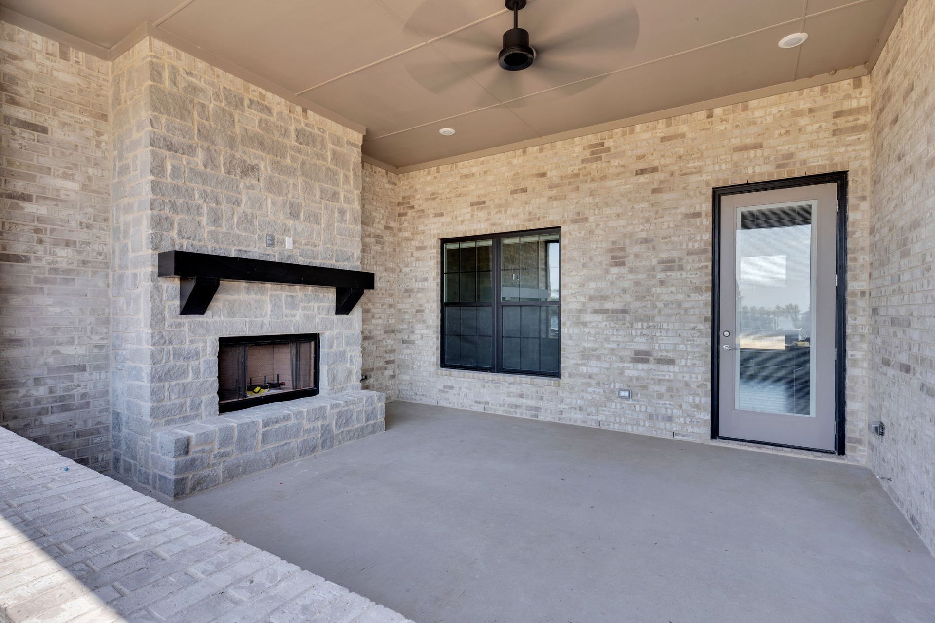 covered patio with stone fireplace and outdoor living space
