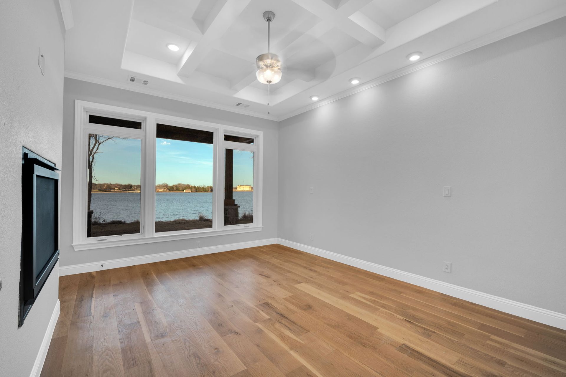 empty living room with tray ceiling and large windows
