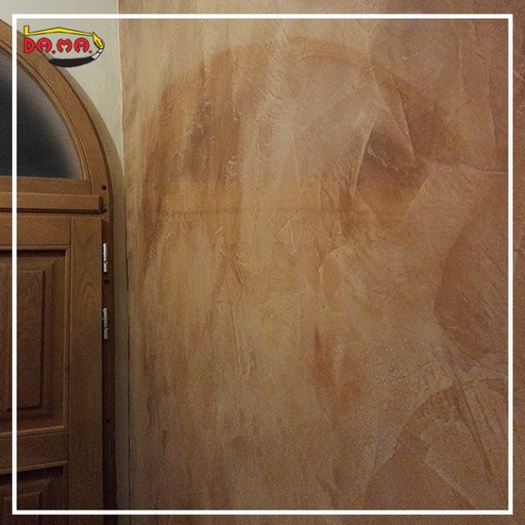 Parete con texture beige, corridoio con una porta aperta.