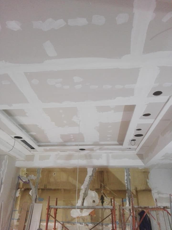 Soffitto con illuminazione a incasso, in costruzione. Cartongesso installato, grezzo; fori presenti. Ponteggio visibile sotto.