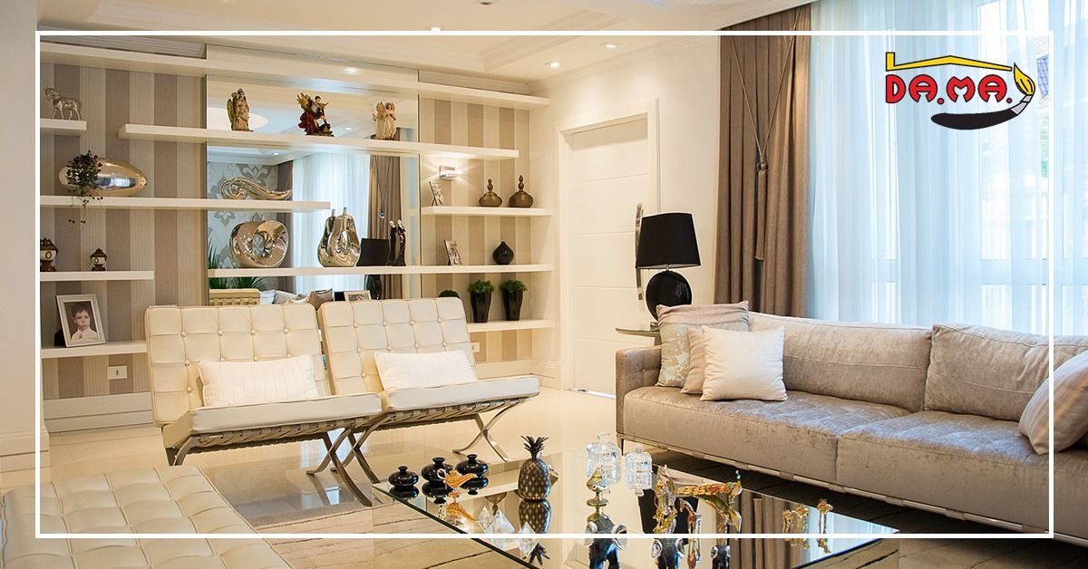 Soggiorno con mobili beige, tavolino da caffè con specchio e mensole con decorazioni.