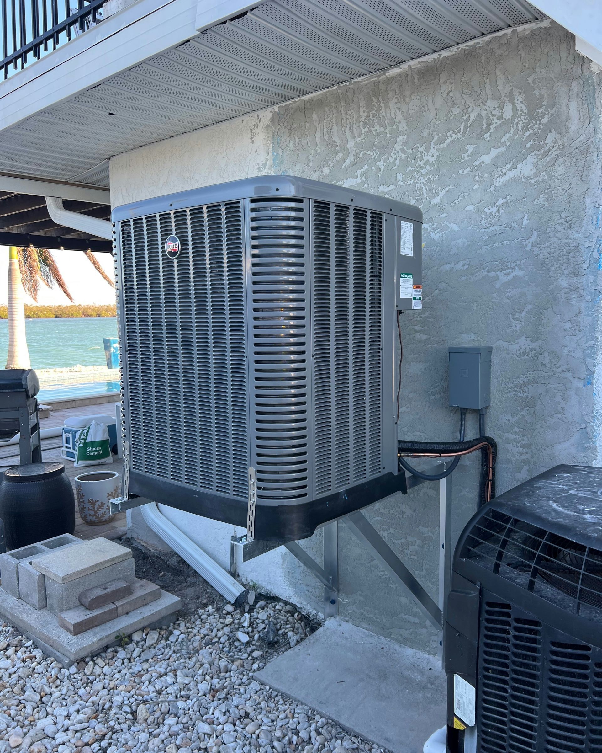Gray air conditioning unit mounted on a stucco wall.