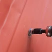 A drill drilling into a red surface.