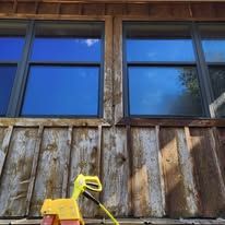Wooden building with blue-tinted windows. Yellow cleaning tool on the weathered wood facade.