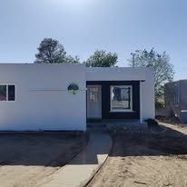 White house exterior with dark door and windows against a blue sky.
